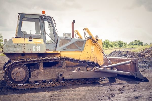 A powerful bulldozer on muddy construction ground under a cloudy sky.