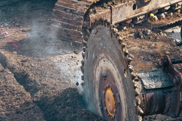 Detailed view of a large industrial saw cutting through earth, showcasing the power of heavy machinery.