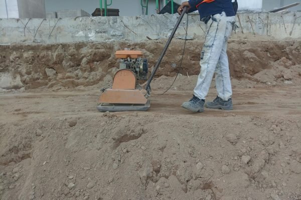 A construction worker using a soil compactor outdoors for groundwork.